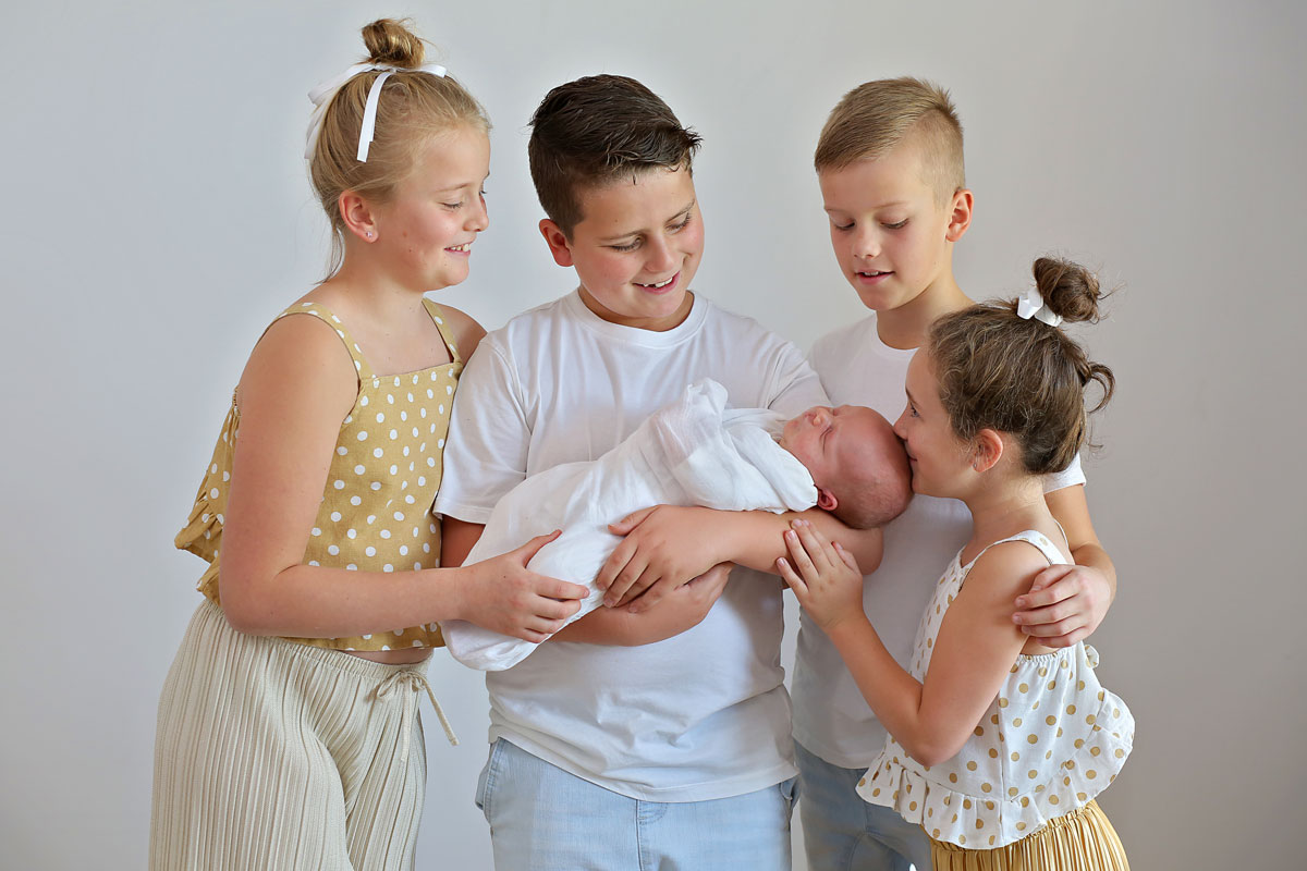 Four children holding new baby for a portrait